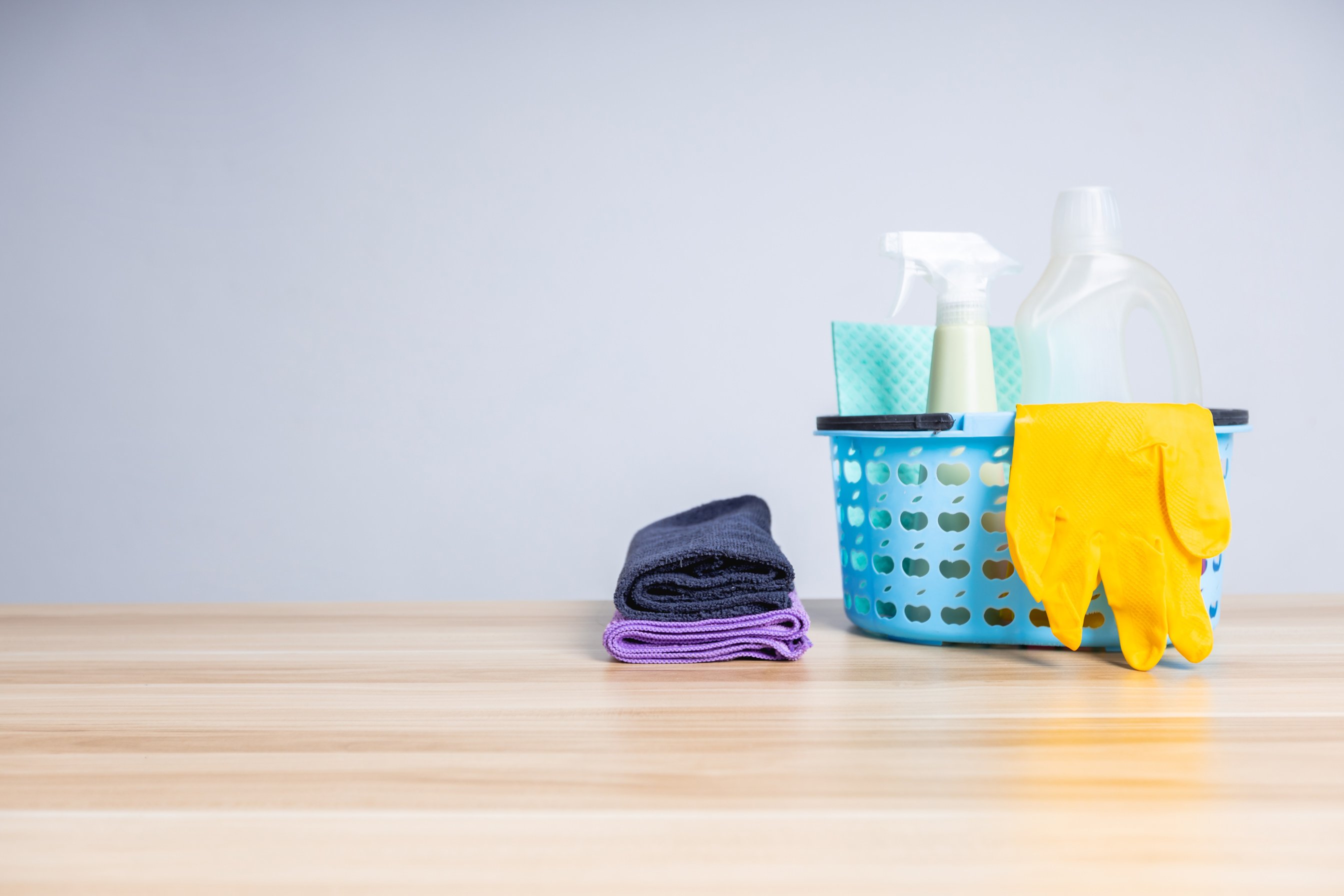 Basket of cleaning supplies on wooden table, cleaning